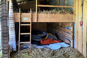 Stockbetten mit Stroh gefüllt und mit Schlafsäcken.