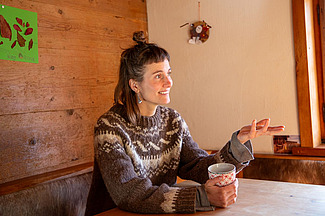  Julia Meier Maggini en conversation, une tasse de thé à la main, assise à table.