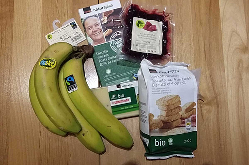 Sur une table, différents produits bio: bananes, une paque de chocolet, betteraves rouges en salade, fromage, biscuits.
